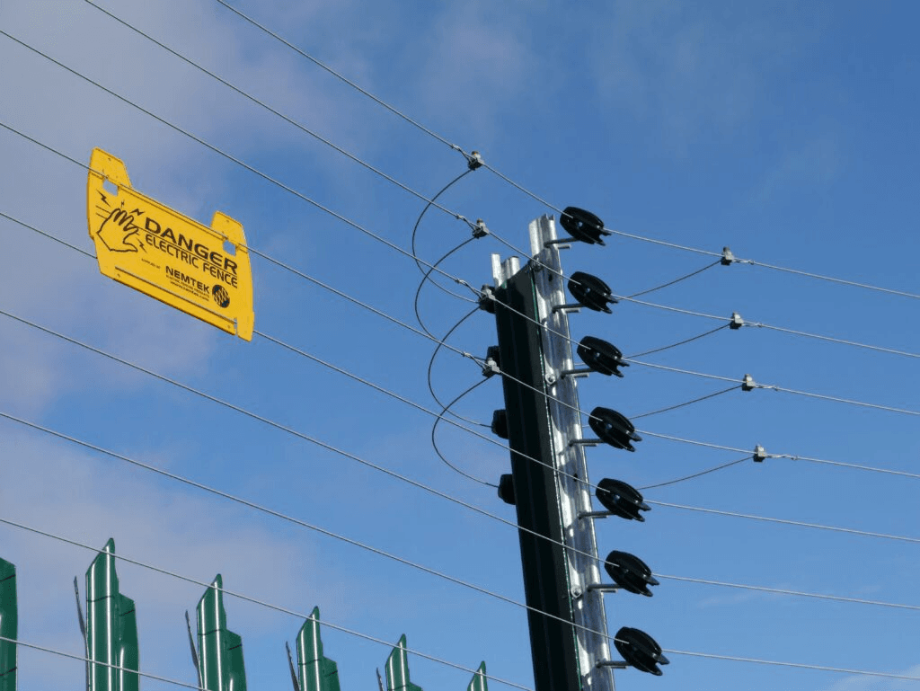 Electric fence wires with insulators and a danger warning sign on a perimeter post